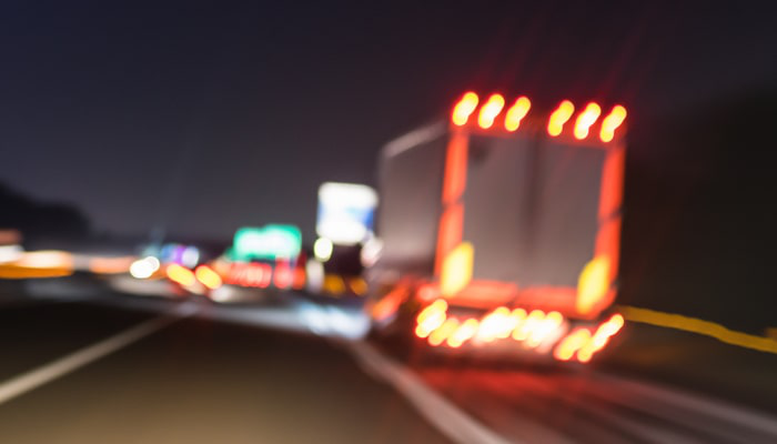 Stock image of truck on highway at night.